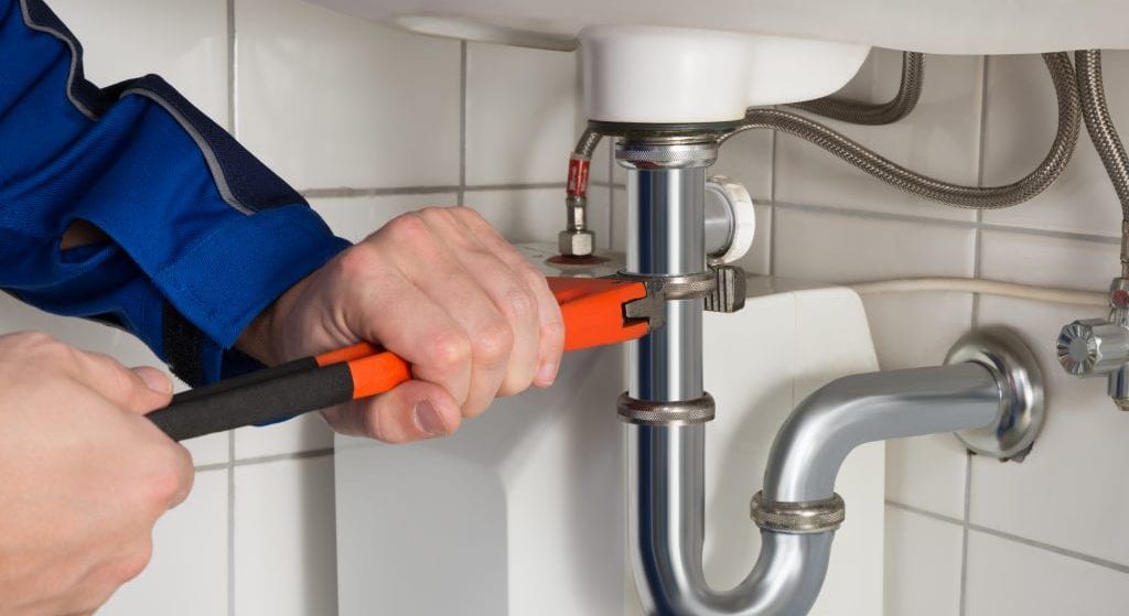 Licensed water treatment specialist installing a whole-home filtration system on a residential main line